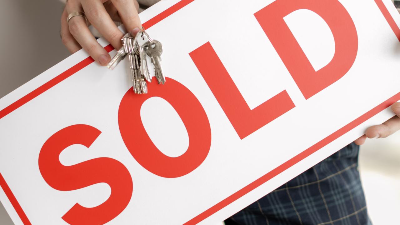 Person holding a sign saying sold
