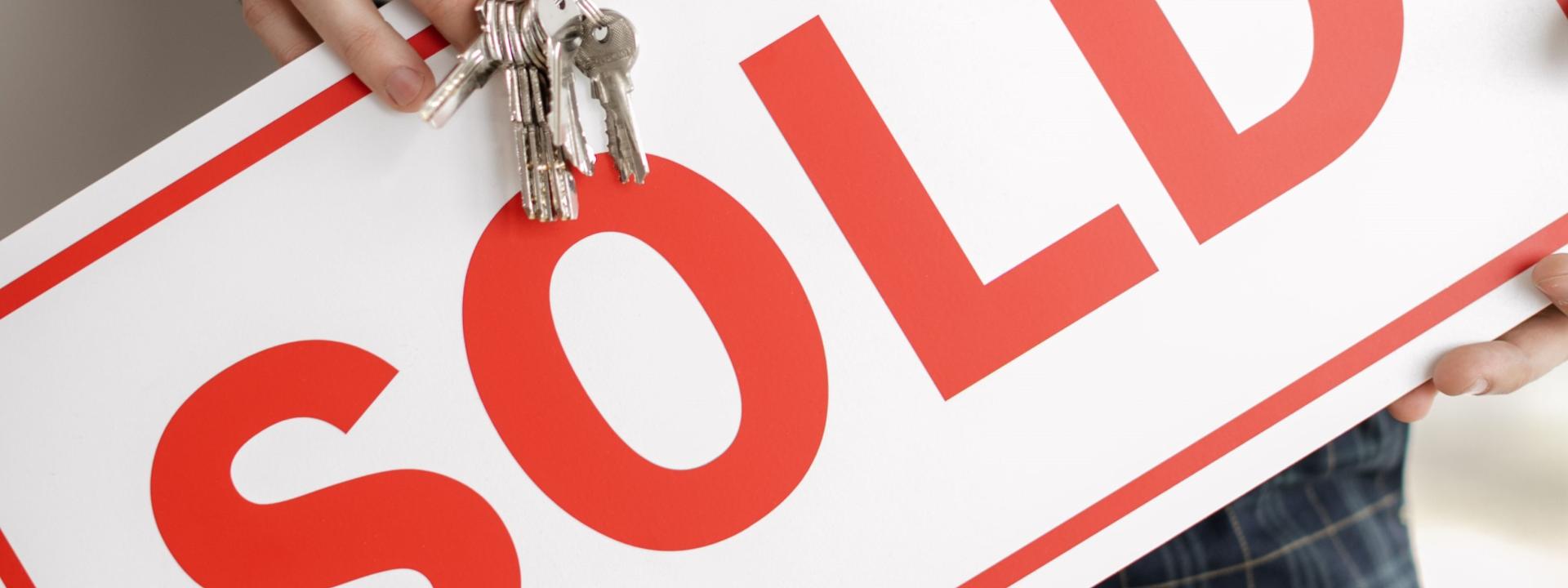 Person holding a sign saying sold