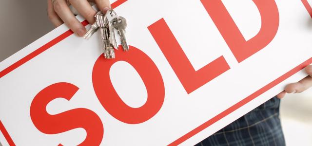 Person holding a sign saying sold